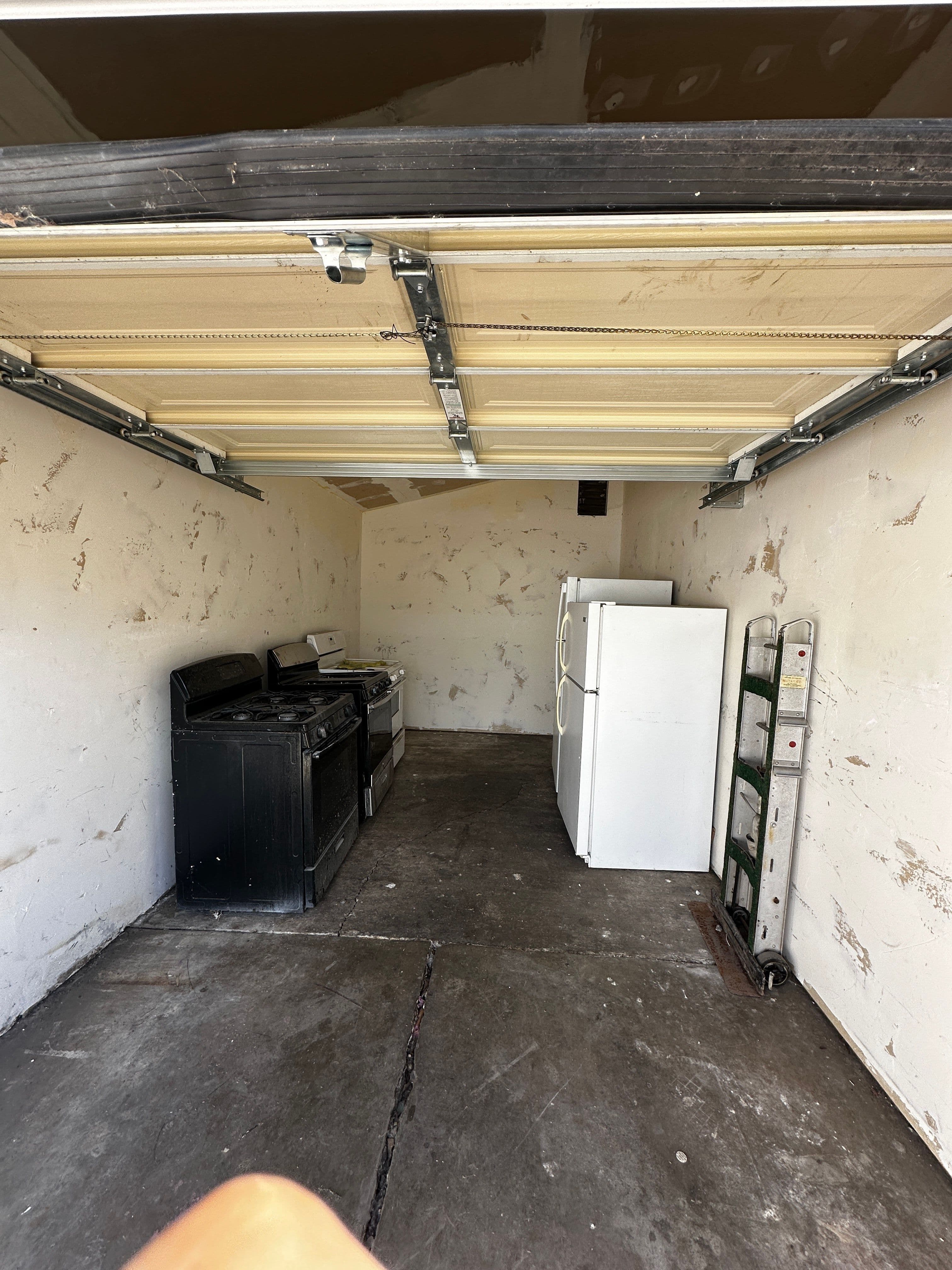 Unfinished garage interior with bare walls and disconnected appliances before the ADU conversion